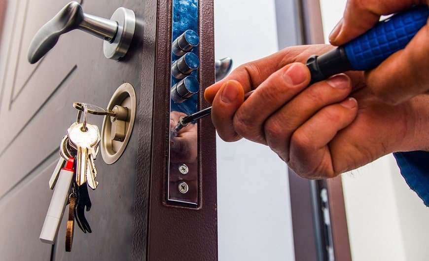 un serrurier dévissant une serrure de porte avec un tournevis